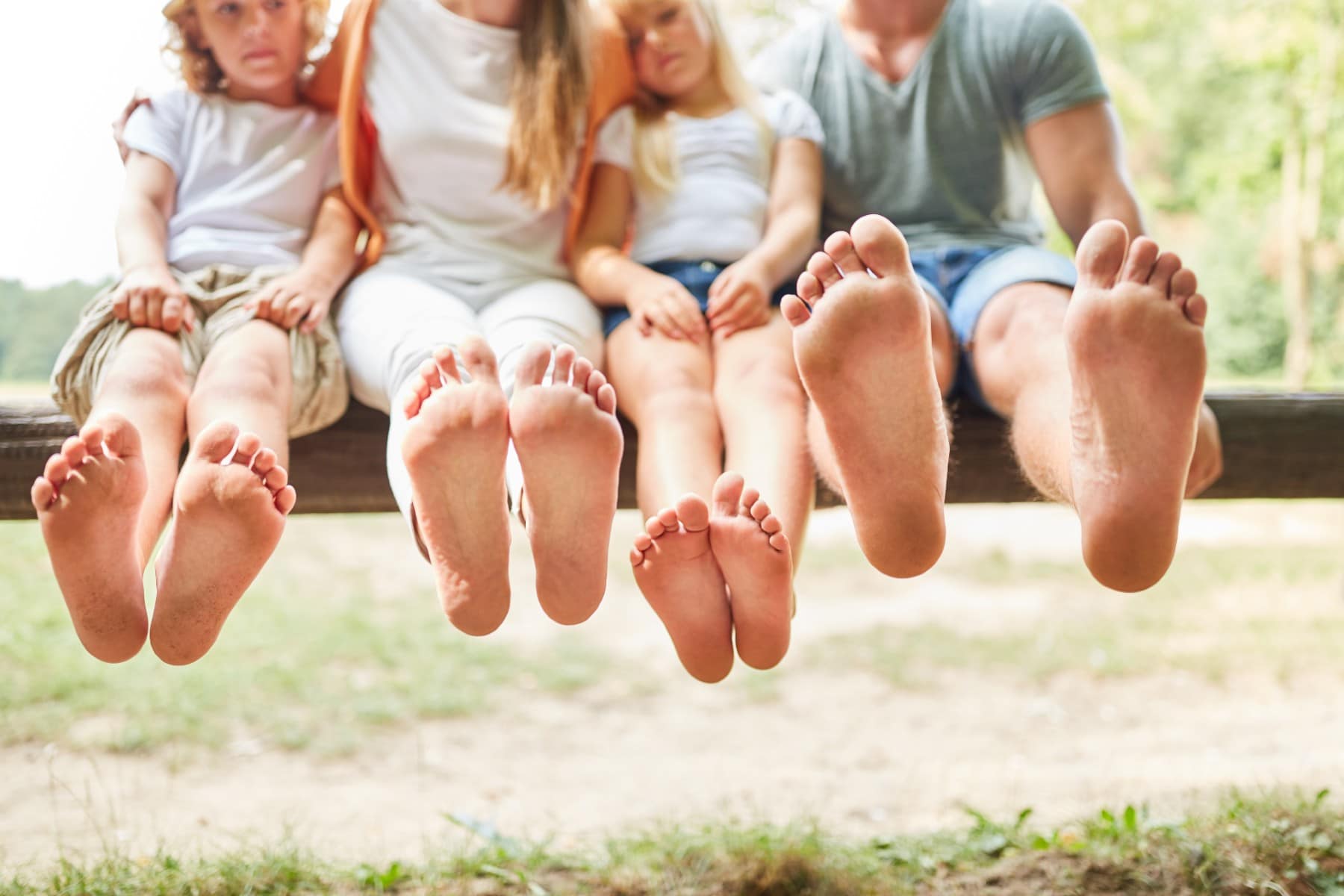 parents and children sitting on a bench with their feet out with a focus on their feet